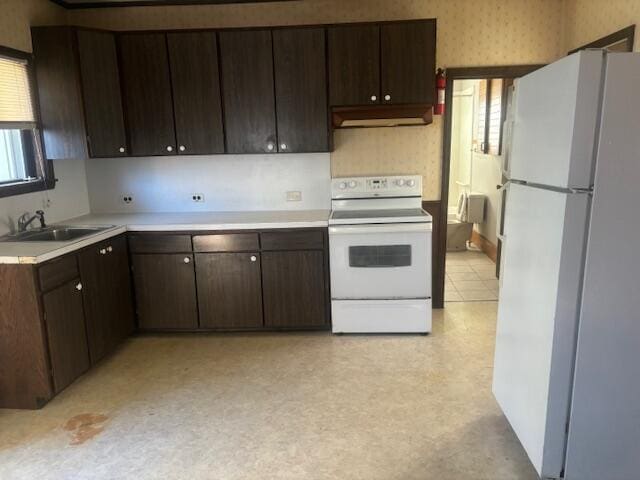 kitchen featuring white appliances, dark brown cabinetry, and sink