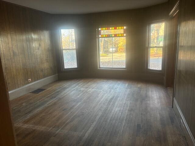 unfurnished dining area featuring dark hardwood / wood-style floors, a wealth of natural light, and wooden walls