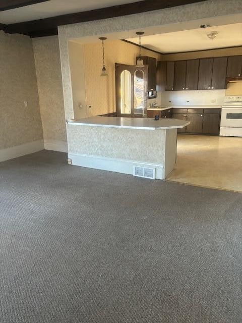 kitchen featuring dark brown cabinets, white range oven, light colored carpet, beam ceiling, and decorative light fixtures