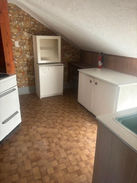 additional living space featuring a textured ceiling, sink, and lofted ceiling