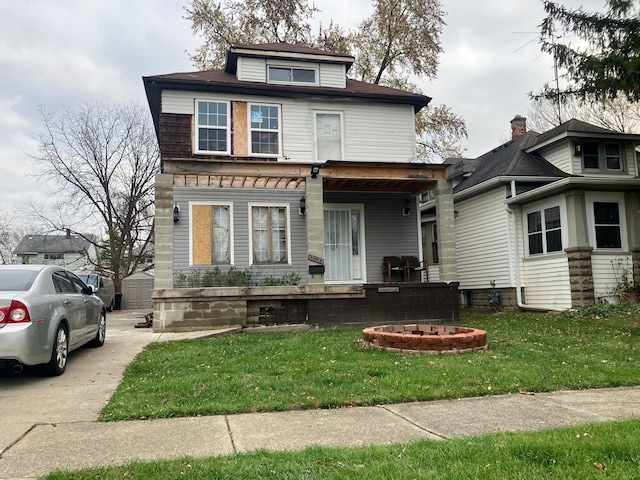 view of front of property with a porch, a front yard, and an outdoor fire pit