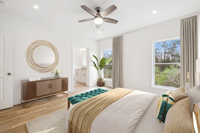 bedroom featuring ceiling fan, light hardwood / wood-style floors, and ensuite bath