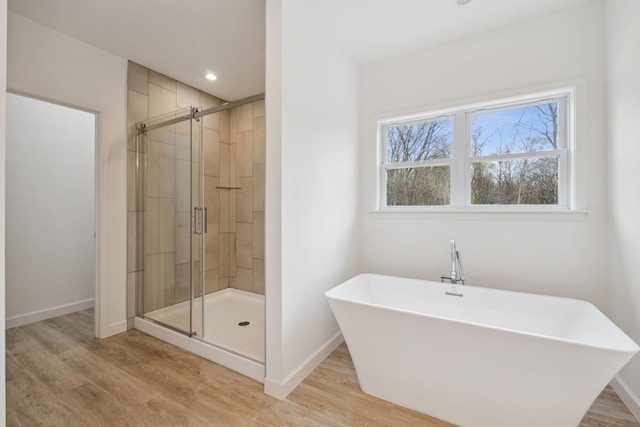 bathroom with hardwood / wood-style floors and independent shower and bath