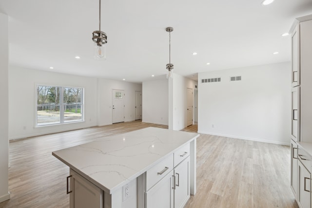 kitchen featuring white cabinetry, a kitchen island, hanging light fixtures, and light wood-type flooring