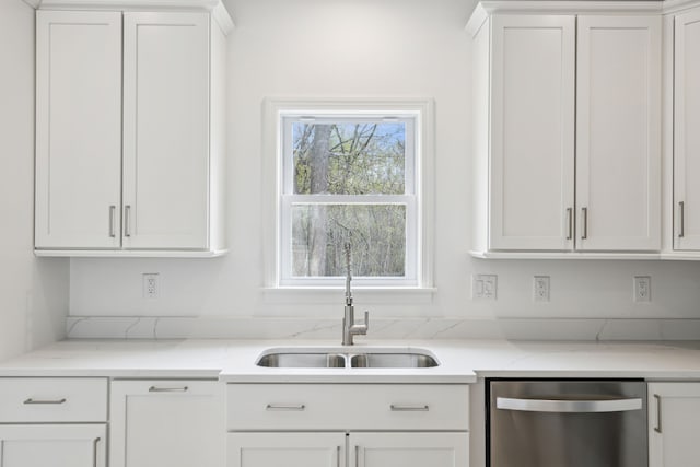 kitchen featuring white cabinets, light stone counters, stainless steel dishwasher, and sink