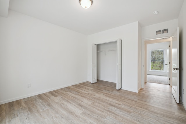 unfurnished bedroom with light wood-type flooring and a closet