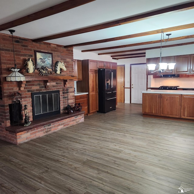 living room featuring a chandelier, a fireplace, beamed ceiling, and wood-type flooring