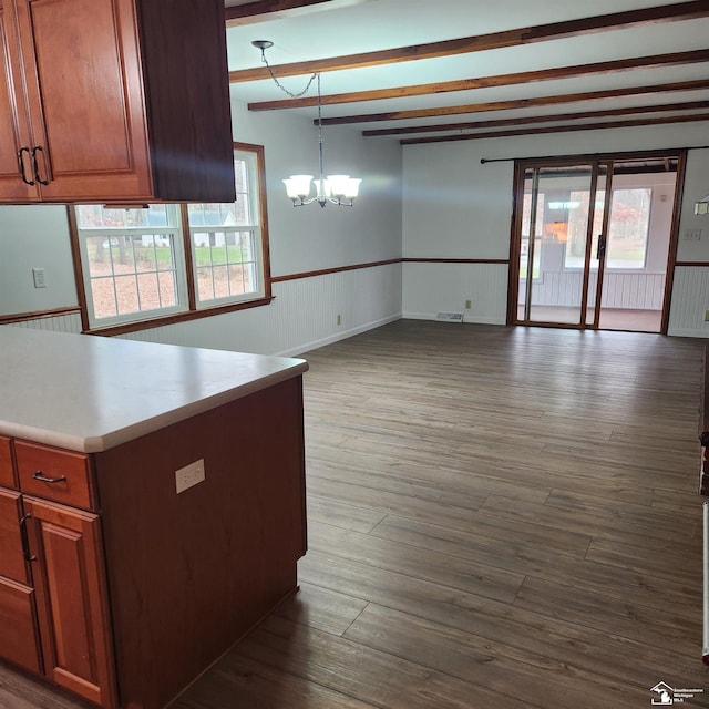 kitchen featuring beamed ceiling, dark wood-type flooring, hanging light fixtures, and a chandelier