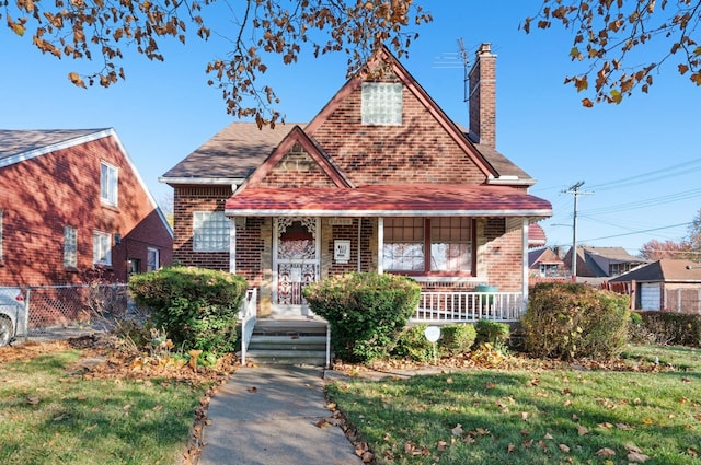 english style home with a porch and a front lawn