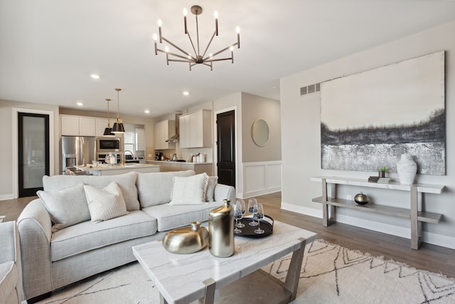 living room with a notable chandelier, wood-type flooring, and sink