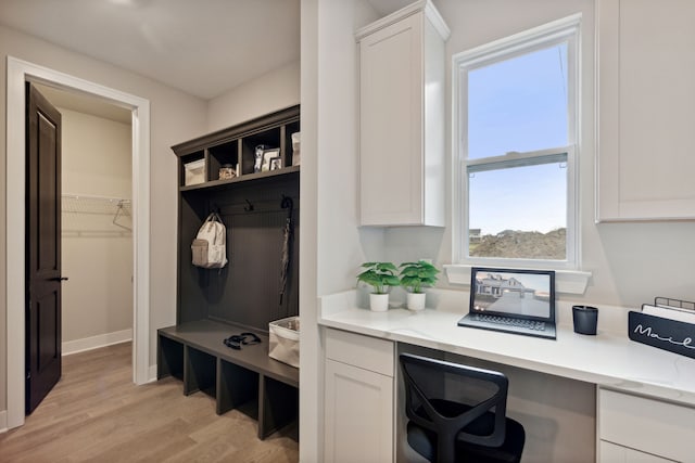 mudroom featuring built in desk and light wood-type flooring