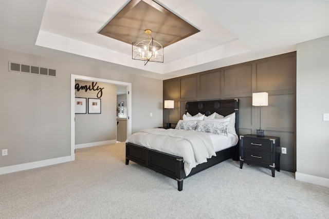 carpeted bedroom featuring a chandelier and a tray ceiling