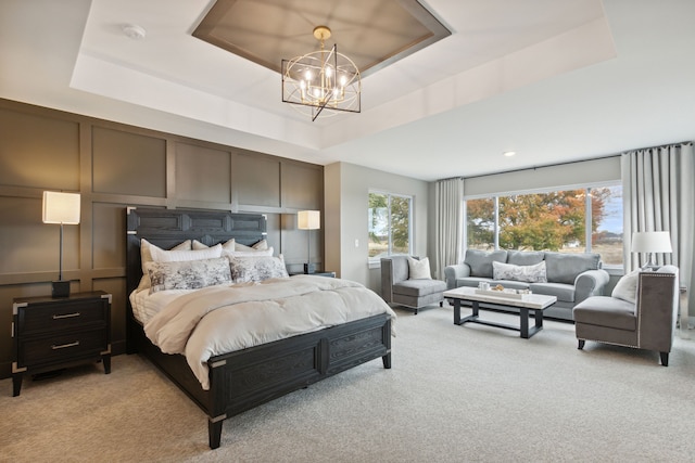 carpeted bedroom featuring a raised ceiling and a chandelier