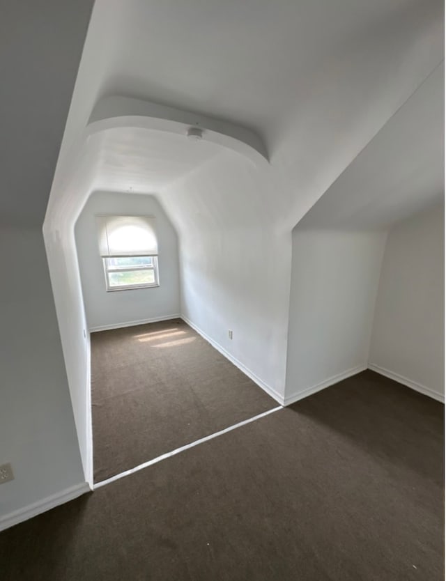 bonus room featuring dark carpet and lofted ceiling