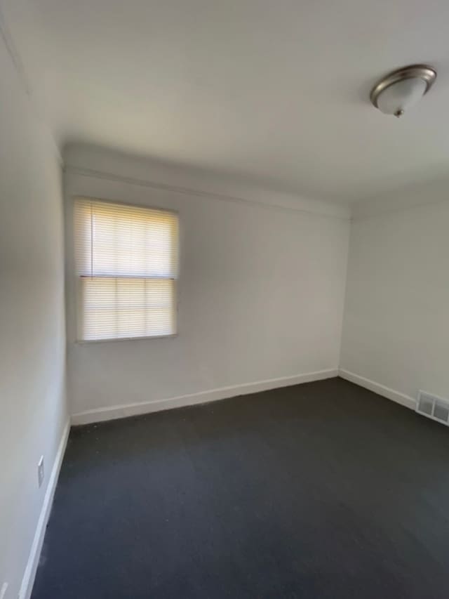 spare room featuring dark colored carpet