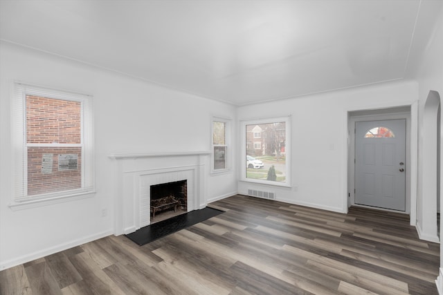 unfurnished living room featuring dark hardwood / wood-style flooring and a brick fireplace