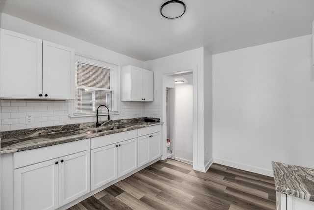 kitchen featuring dark hardwood / wood-style flooring, sink, white cabinets, and dark stone countertops