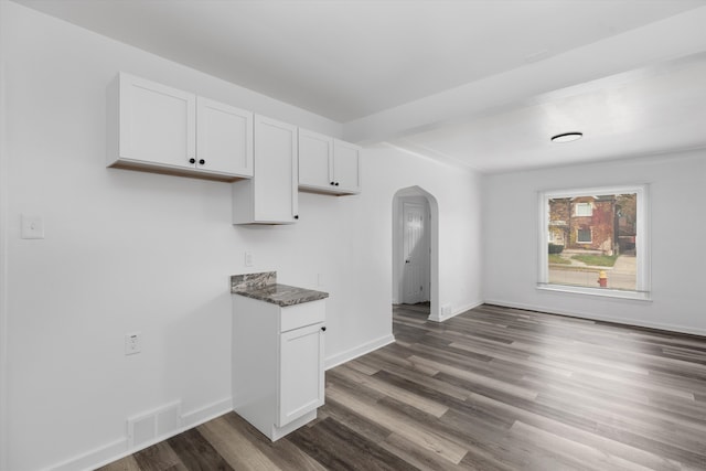 kitchen featuring white cabinets, dark hardwood / wood-style flooring, and dark stone countertops