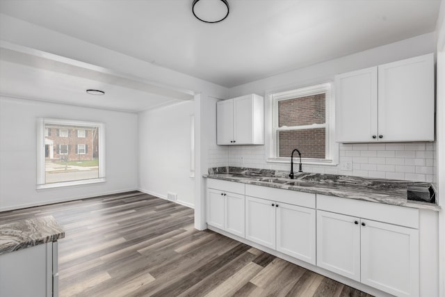 kitchen featuring white cabinetry, sink, tasteful backsplash, dark hardwood / wood-style flooring, and dark stone counters