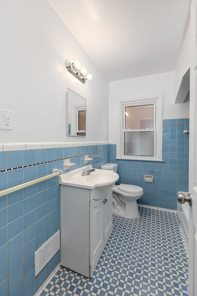 bathroom with vanity, tile walls, and toilet