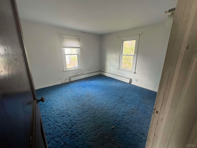 carpeted spare room featuring baseboard heating