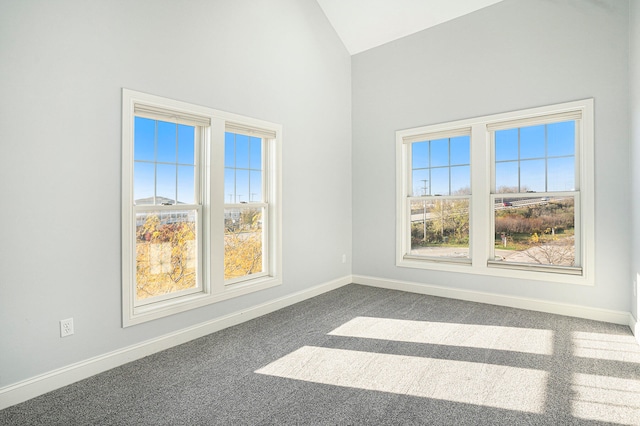 unfurnished room with dark colored carpet, plenty of natural light, and vaulted ceiling