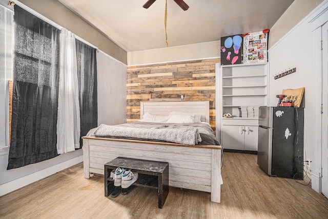 bedroom with hardwood / wood-style floors, ceiling fan, and stainless steel refrigerator