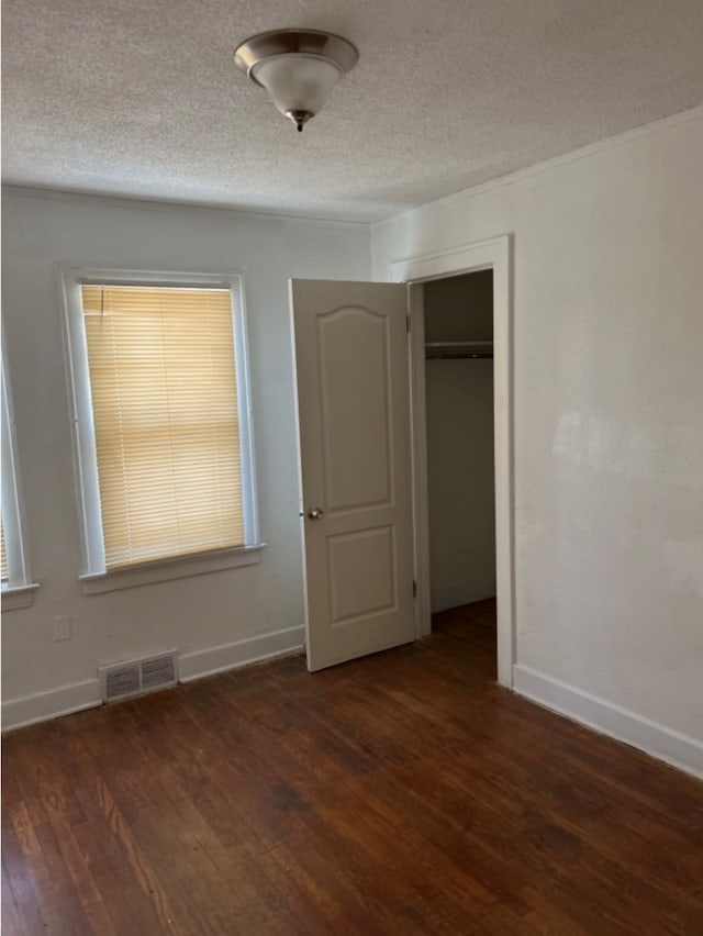 unfurnished bedroom with dark hardwood / wood-style floors, a textured ceiling, and a closet