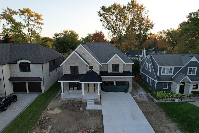 view of front of property with a garage, covered porch, a standing seam roof, and concrete driveway