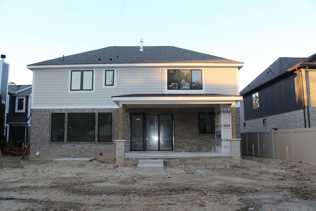 rear view of property with fence, a porch, and brick siding