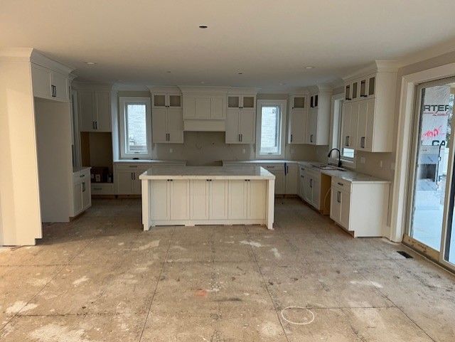 kitchen with white cabinetry, crown molding, a center island, and sink