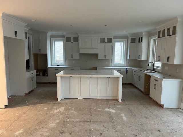 kitchen with white cabinetry, crown molding, sink, and a kitchen island