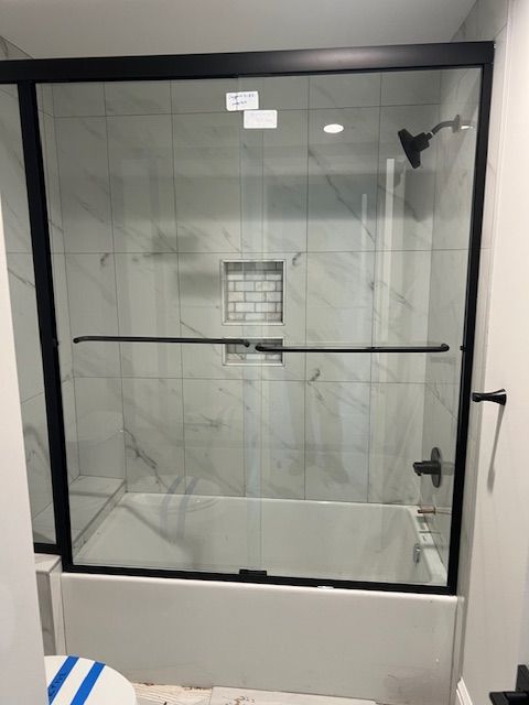 bathroom with toilet and shower / bath combination with glass door