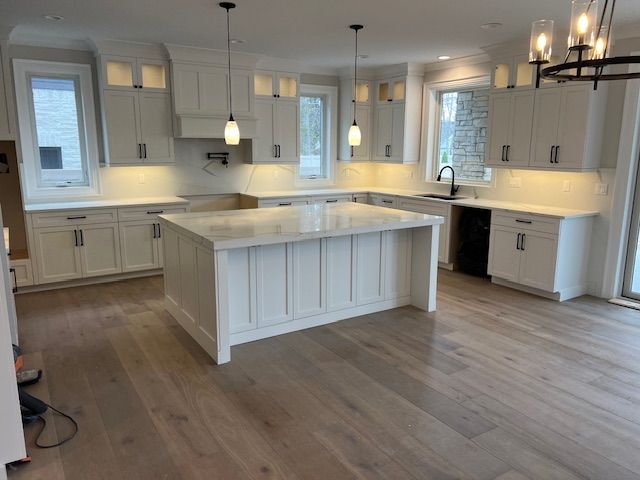kitchen featuring a sink, a center island, white cabinets, and wood finished floors
