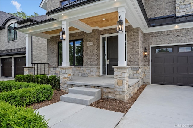 2182 Buckingham Ave, Birmingham, MI 48009 - view of exterior entry with a porch, a garage, concrete driveway, and stone siding