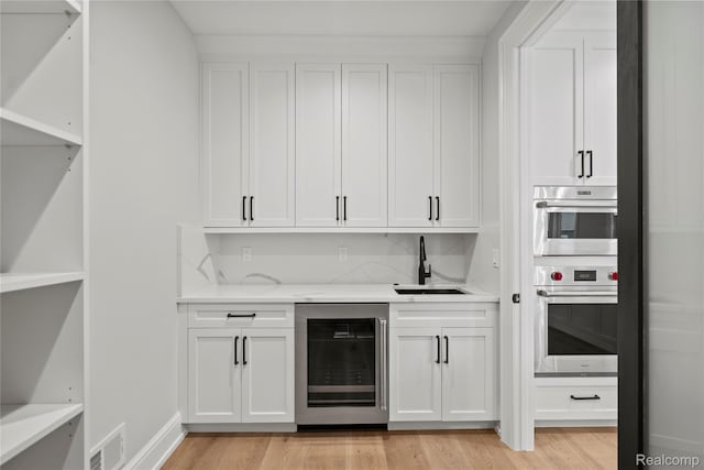 2182 Buckingham Ave, Birmingham, MI 48009 - indoor wet bar featuring wine cooler, stainless steel oven, and light wood-style floors