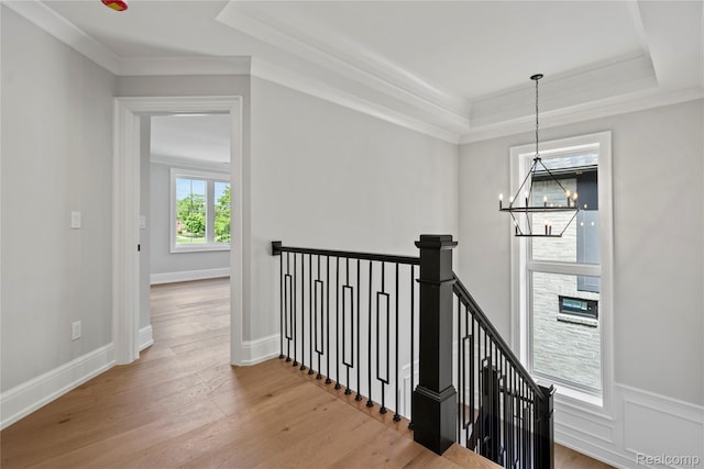 2182 Buckingham Ave, Birmingham, MI 48009 - corridor featuring an upstairs landing, a tray ceiling, a chandelier, wood finished floors, and crown molding