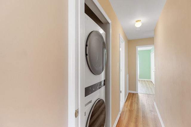 laundry room featuring stacked washer and dryer and light hardwood / wood-style floors