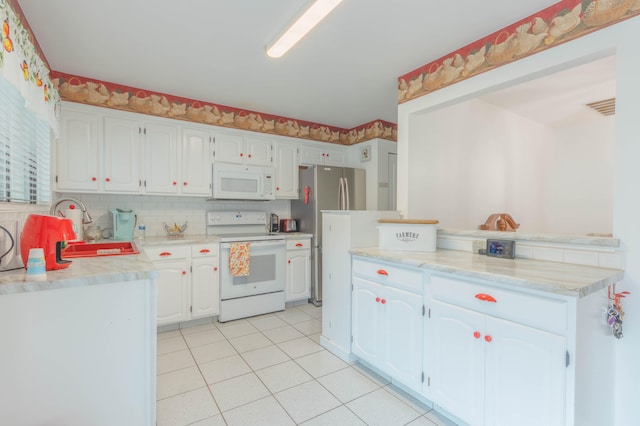 kitchen with backsplash, white appliances, sink, white cabinets, and light tile patterned flooring