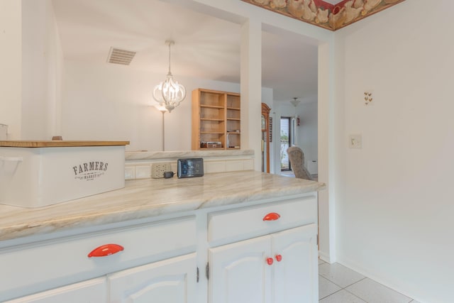 kitchen featuring white cabinetry, light tile patterned floors, light stone counters, and decorative light fixtures