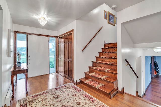 entryway featuring a chandelier, wood-type flooring, and vaulted ceiling