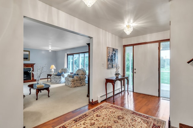 entrance foyer with wood-type flooring, a baseboard radiator, and an inviting chandelier