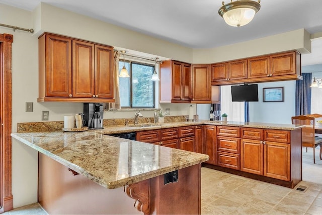 kitchen with pendant lighting, sink, light stone countertops, kitchen peninsula, and a breakfast bar area