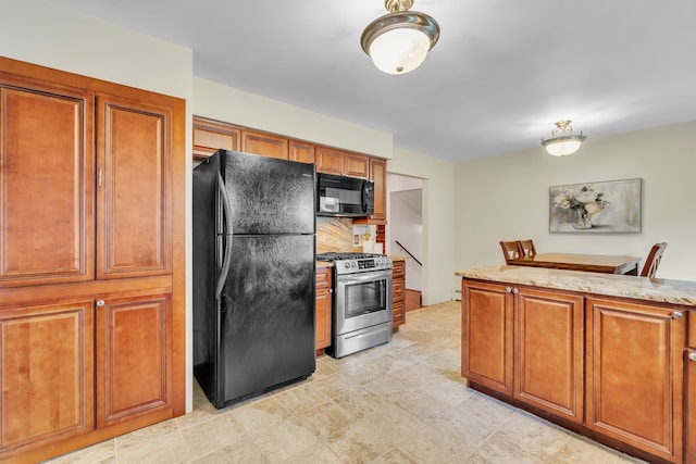 kitchen with tasteful backsplash, light stone counters, and black appliances