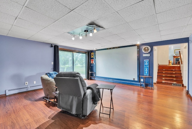 cinema with wood-type flooring, a paneled ceiling, and a baseboard radiator