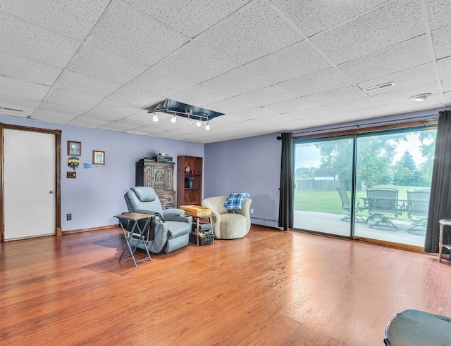 sitting room with wood-type flooring, a paneled ceiling, and a baseboard heating unit