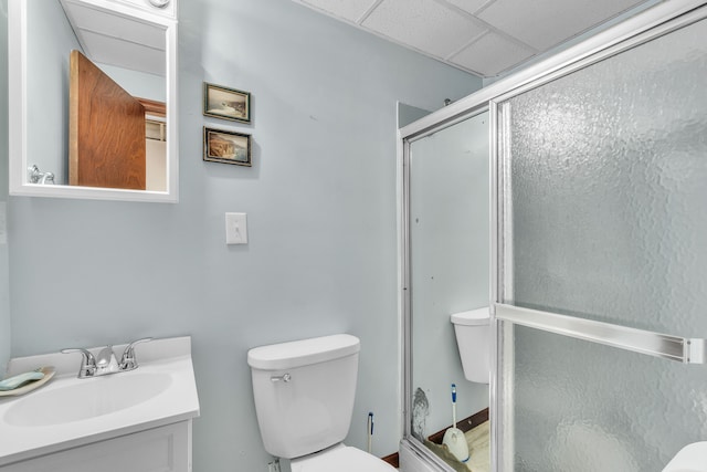 bathroom with vanity, a paneled ceiling, toilet, and a shower with door