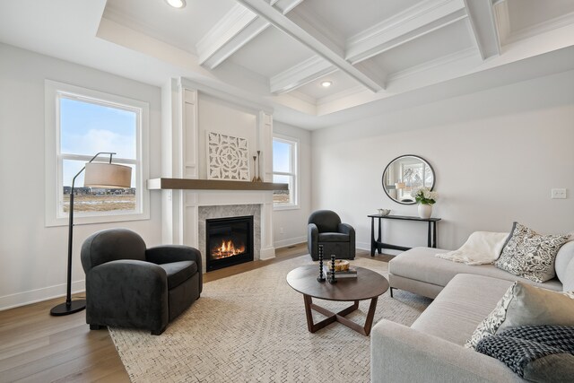 living area featuring baseboards, coffered ceiling, a fireplace, and light wood finished floors