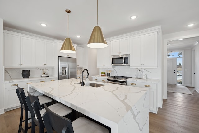 kitchen with a center island with sink, appliances with stainless steel finishes, white cabinets, and a sink