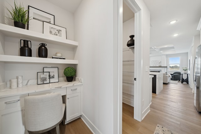 home office featuring baseboards, built in study area, light wood-style flooring, a fireplace, and recessed lighting